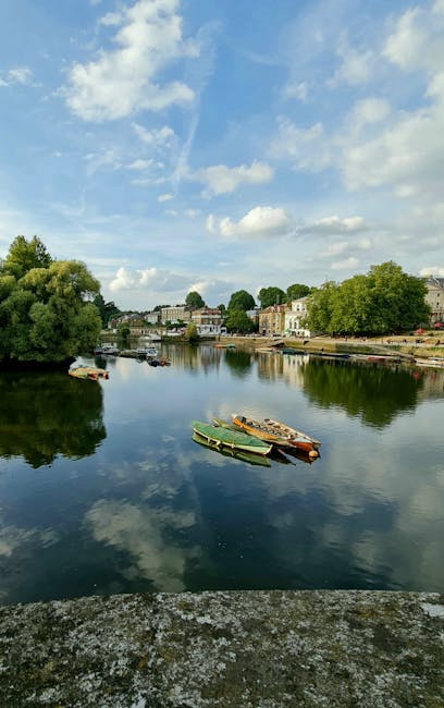 A view of residential buildings along the water's edge in Bromley-by-Bow, with a canal reflecting the illuminated windows and streetlights. The buildings include a mix of traditional brick houses and 